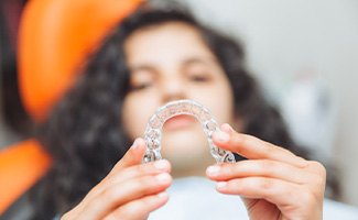 Teenager holding Invisalign aligner in treatment chair