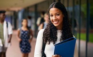 Teenage girl smiling while holding blue binder