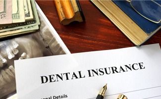 Dental insurance paperwork on wooden desk with X-ray