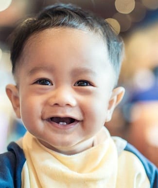 infant sitting in a highchair and smiling 