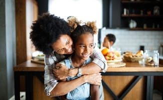 parent hugging their child in a kitchen