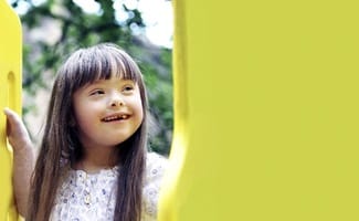 child smiling and playing outside on a playset