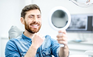 dental patient admiring his smile in a mirror