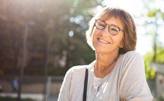 Senior woman with glasses outside and smiling