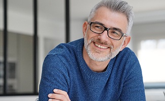 man with glasses smiling with arms crossed 