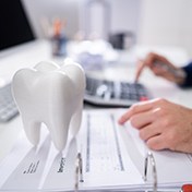 Model tooth resting on a patient invoice next to dentist