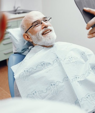 a patient smiling about his brand-new implant dentures