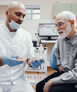a dentist explaining how implant dentures work to his patient