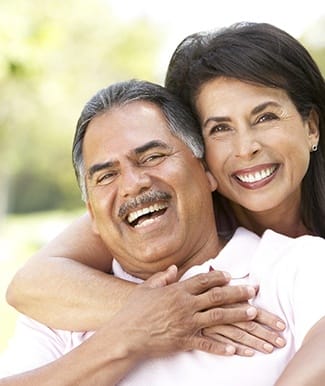 Smiling couple outside with dental implants in Ocala