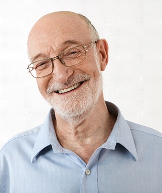 Older man with grey beard smiling while wearing glasses