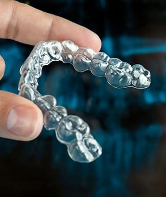 close-up of a person’s hand holding an Invisalign aligner 