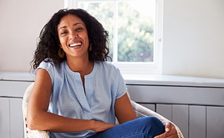 Woman in blue shirt smiling while relaxing at home