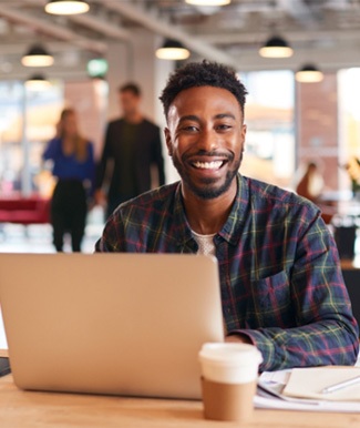 Man smiling while working on laptop in office