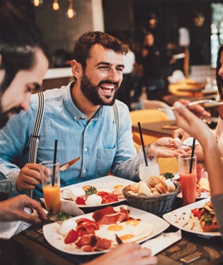 Group of friends smiling while eating lunch together in restaurant