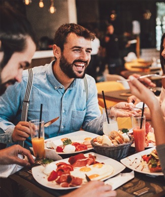 Group of friends smiling while eating lunch together in restaurant