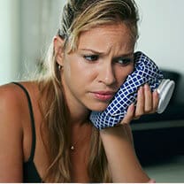 woman holding ice pack on cheek