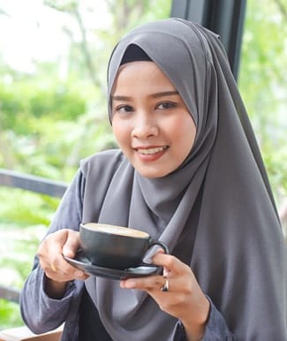 person smiling and holding a cup of coffee