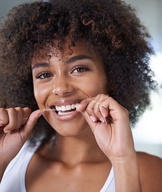 Woman smiling while flossing her teeth