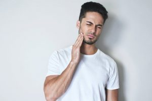 A man holding his mouth in pain.