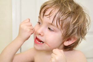 little boy flossing teeth