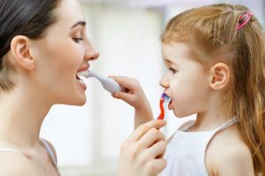 A mother and daughter brushing each other’s teeth.