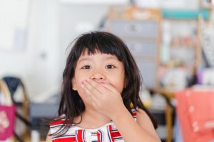 Little girl covers her mouth after hearing cavities lead to tooth infections