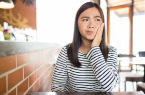 Woman with hand on cheek wonders if she should visit Ocala dentist