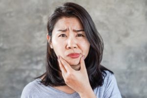 a person holding their mouth because it's swollen
