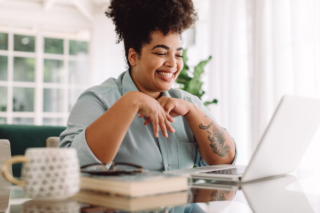 Woman smiling while working on laptop at home